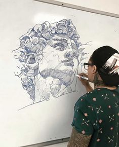 a man drawing on a whiteboard with a marker and pen in front of him