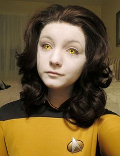 a close up of a person wearing a star trek uniform with yellow eyes and black hair