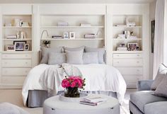 a bedroom with white furniture and pink flowers on the table in front of the bed