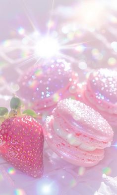 three pink donuts and a strawberry on a white surface with sunbeams in the background