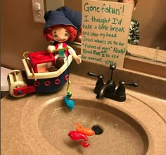 a sink with a toy boat on it and a sign that says gone fishin