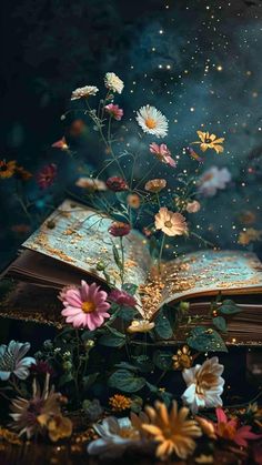 an open book sitting on top of a wooden table next to flowers and stars in the sky