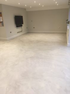 an empty living room with white walls and flooring is seen in this image, there are lights on the ceiling