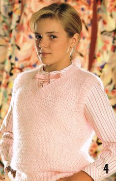 a woman wearing a pink sweater and bow tie