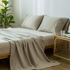 an unmade bed sitting next to a window in a room with white walls and wooden flooring