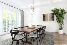 a dining room table with six chairs and a potted plant in the middle of it