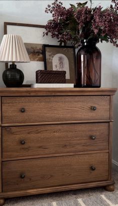 a wooden dresser with flowers and pictures on top