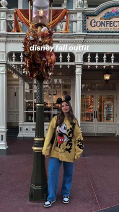 a woman standing next to a lamp post in front of a disney mouse store at disneyland world