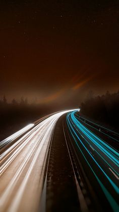 long exposure photograph of highway at night with light streaks on the road and trees in the background