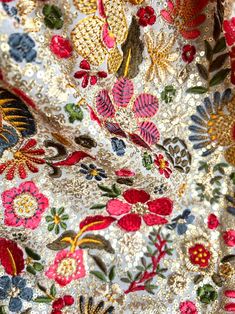 close up view of an embroidered fabric with flowers and leaves in red, yellow, blue, green, orange