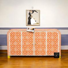 an orange and white sideboard in a room with a painting on the wall behind it