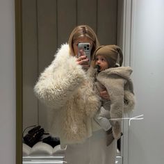 a woman taking a selfie in front of a mirror while holding a small child