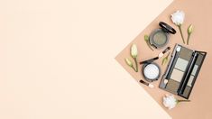 cosmetics and makeup products laid out on top of a beige surface with flowers in the background