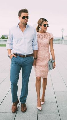 a man and woman are walking down the street wearing blue pants, white shirt and pink dress