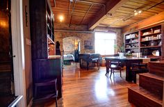 an open living room with wooden flooring and stairs leading up to the dining area