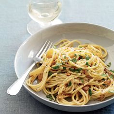 a white bowl filled with pasta and garnished with parsley