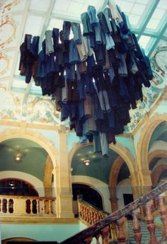 an artistic sculpture hanging from the ceiling in a building with stairs and railings below