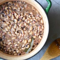 a pot filled with beans next to a wooden spoon