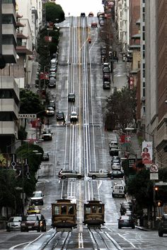 an aerial view of a city street with cars and trolleys on the tracks in front of buildings