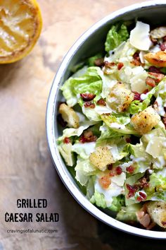 a salad with croutons and bacon in a bowl next to an orange slice