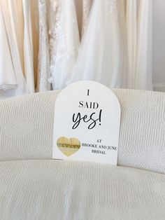 a sign that says i said yes sits on the back of a bed in a bridal gown shop