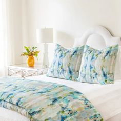 a white bed with blue and green pillows