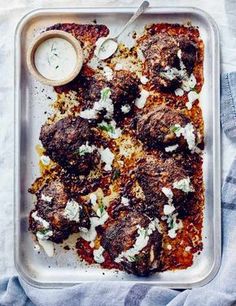 meatballs covered in sauce and parmesan cheese on a tray