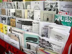 many books are stacked up on a red shelf in front of a wall full of them