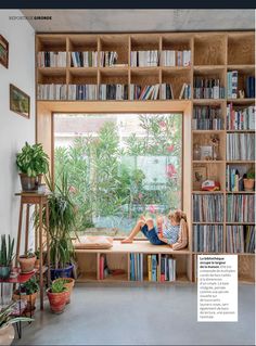 a woman sitting on a window sill in front of a book shelf filled with books