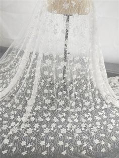 the back of a wedding veil with white flowers on black and white lace over it