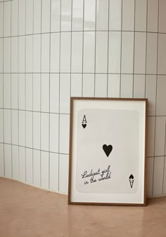 a picture frame sitting on top of a counter next to a wall with tiles and a heart