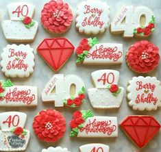 decorated cookies with red and white frosting are arranged on a table for an anniversary celebration