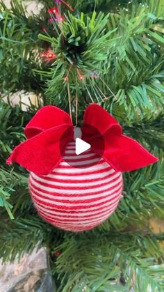 a red and white ornament hanging from a christmas tree with a bow on it