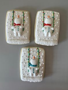 three decorated cookies sitting on top of a white table next to each other with frosting