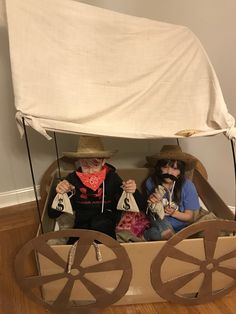 two people sitting in a cart made out of cardboard