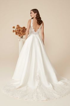 a woman in a white wedding dress standing next to a vase with flowers on it