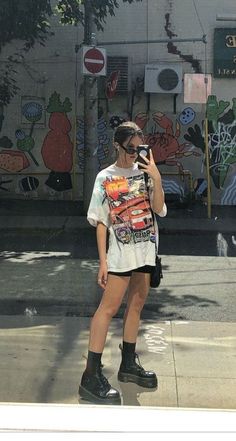 a woman taking a selfie in front of a building with graffiti on the walls