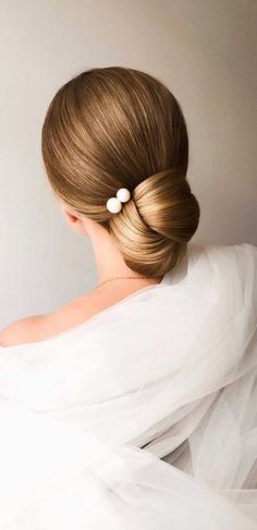 a woman with her hair in a low bun, wearing a white dress and veil