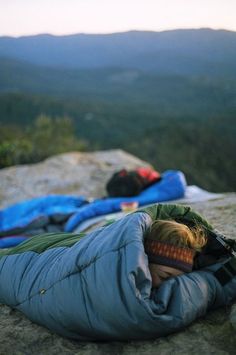 two people sleeping on top of a mountain