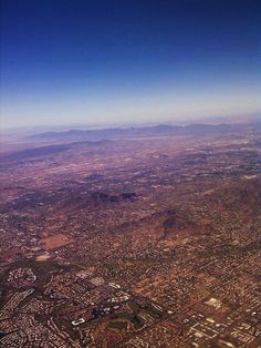 the view from an airplane looking down on a large city and mountains in the distance