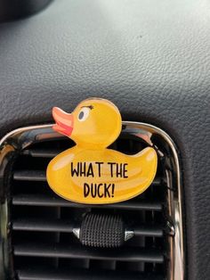 a rubber duck sitting on the dashboard of a car with what the duck? written on it