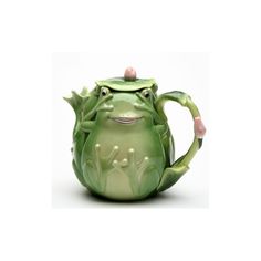 a green ceramic teapot with a smiling frog on it's face and arms