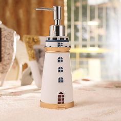 a white and gold lighthouse shaped soap dispenser on top of a bed