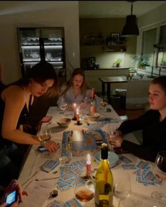 a group of people sitting around a table with wine glasses and candles in front of them