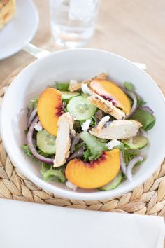 a white bowl filled with salad sitting on top of a table next to a fork