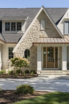 the front of a house with stone and shingles on it's side walk