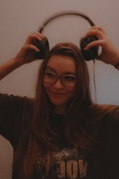 a woman wearing glasses and headphones in front of a mirror with her hands behind her head