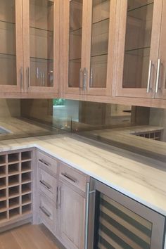 an empty kitchen with wooden cabinets and marble counter tops on the island in front of it