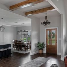 a living room and dining area with hardwood floors, white walls and wood beams in the ceiling