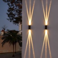 two wall lights on the side of a building with palm trees in front of them